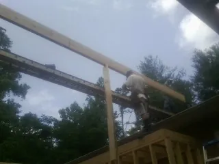 Carpenter setting a ridge beam over a new addition frame — Ice Dam Removal by Roofing Brothers in East Baldwin