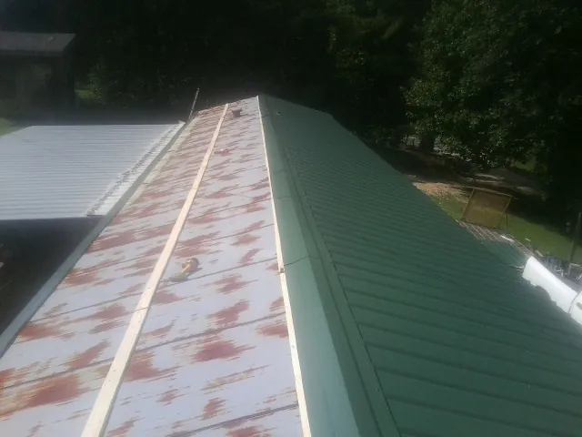 Old rusted panels beside newly installed green metal roofing — Wind Damage Roof Repair by Roofing Brothers in East Baldwin