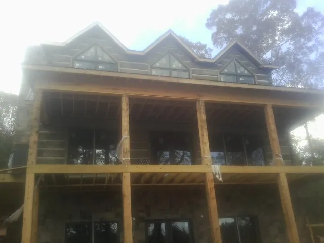 Dormers and porch framing on a large log home under construction — Roof Coating work by our crew in East Baldwin