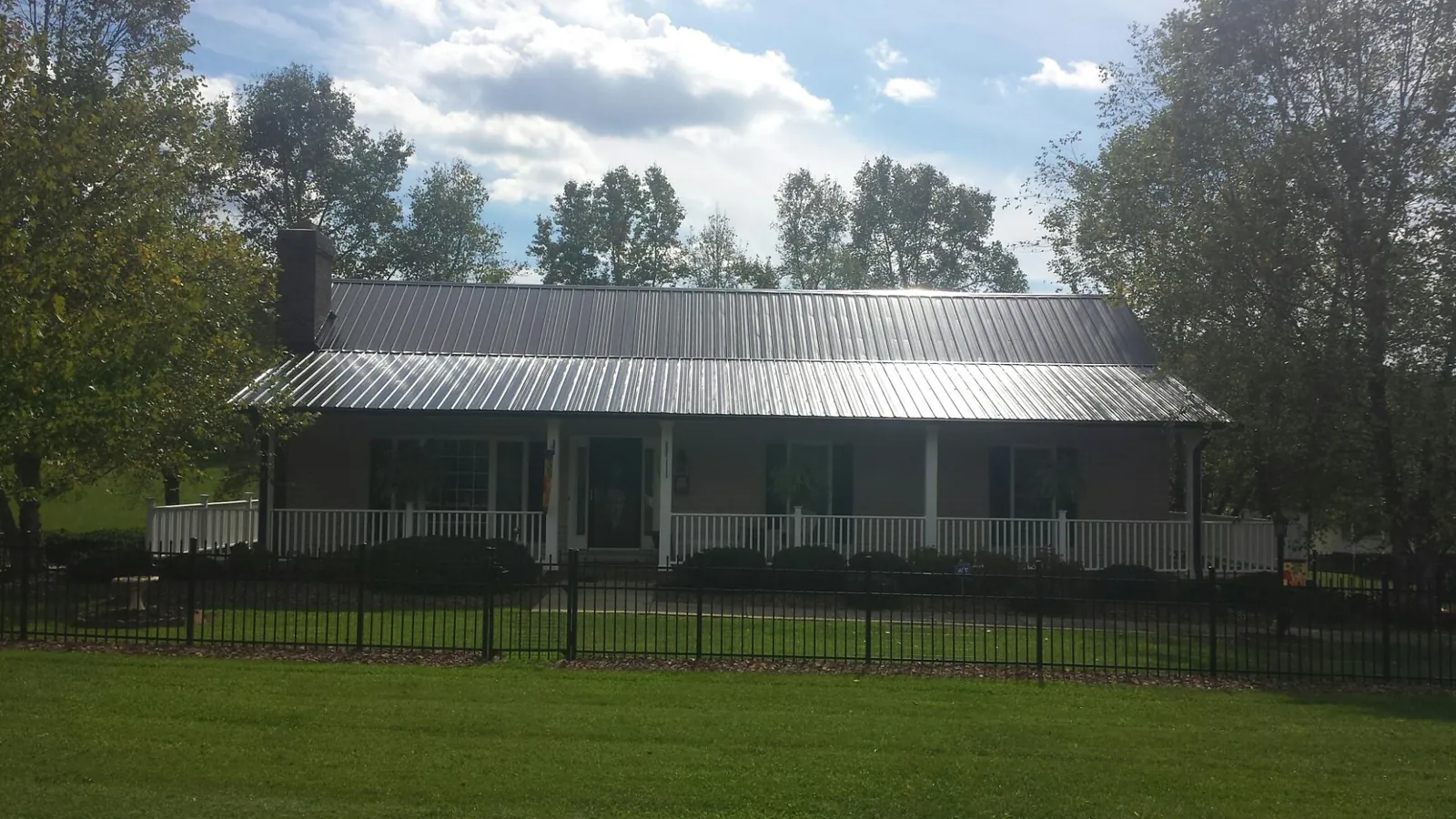 Gray metal roof on a brick ranch with a full width front porch — Gutter Guard Installation work by our crew in East Baldwin