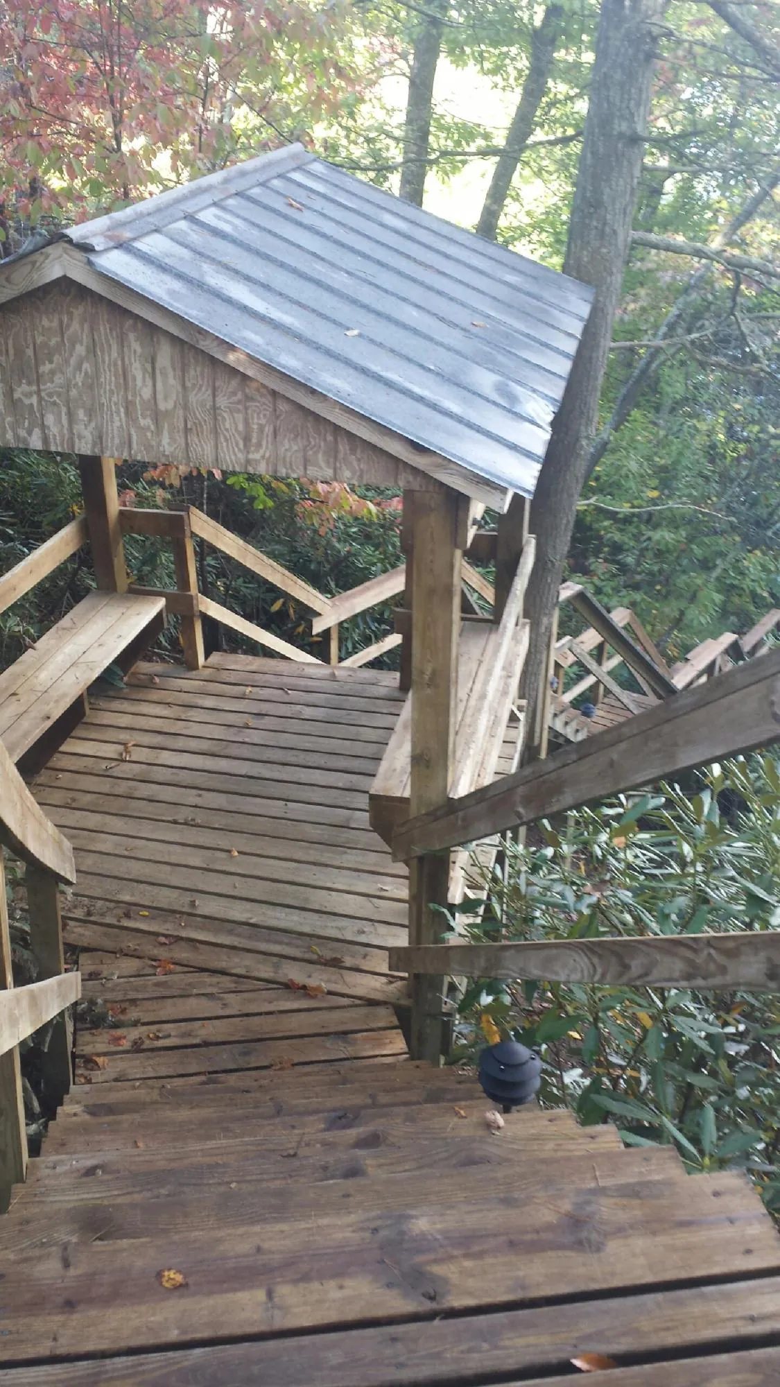 Metal roofed shelter over wooden steps on a wooded walkway — Skylight Repair & Installation work by our crew in East Baldwin