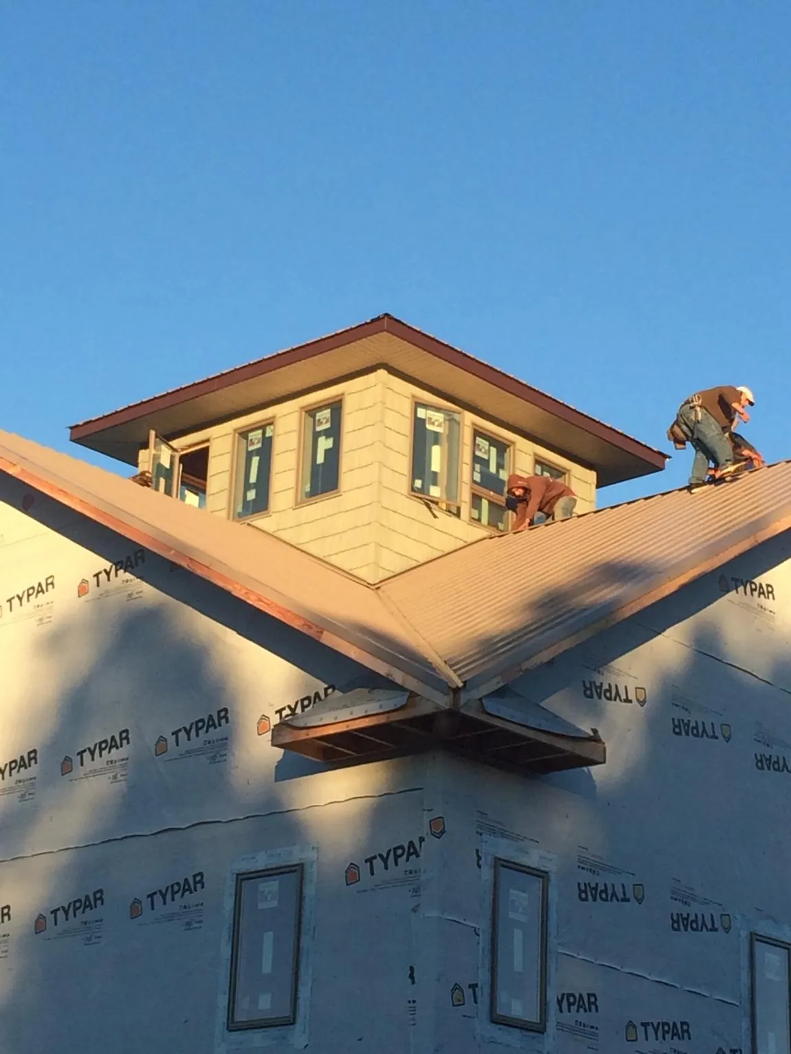 Roofers working around a rooftop cupola on a new metal roof at sunset — Roof Waterproofing in East Baldwin by Roofing Brothers